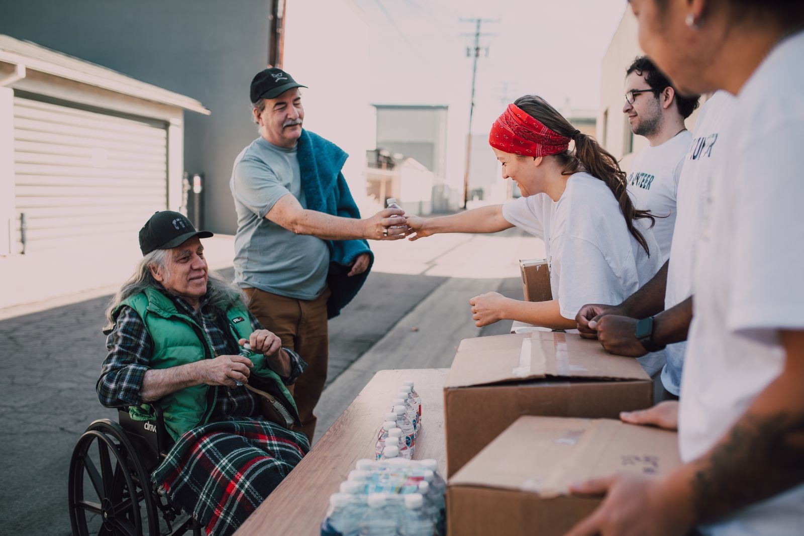 Volunteers distribute water and supplies to people outdoors, promoting community support and kindness