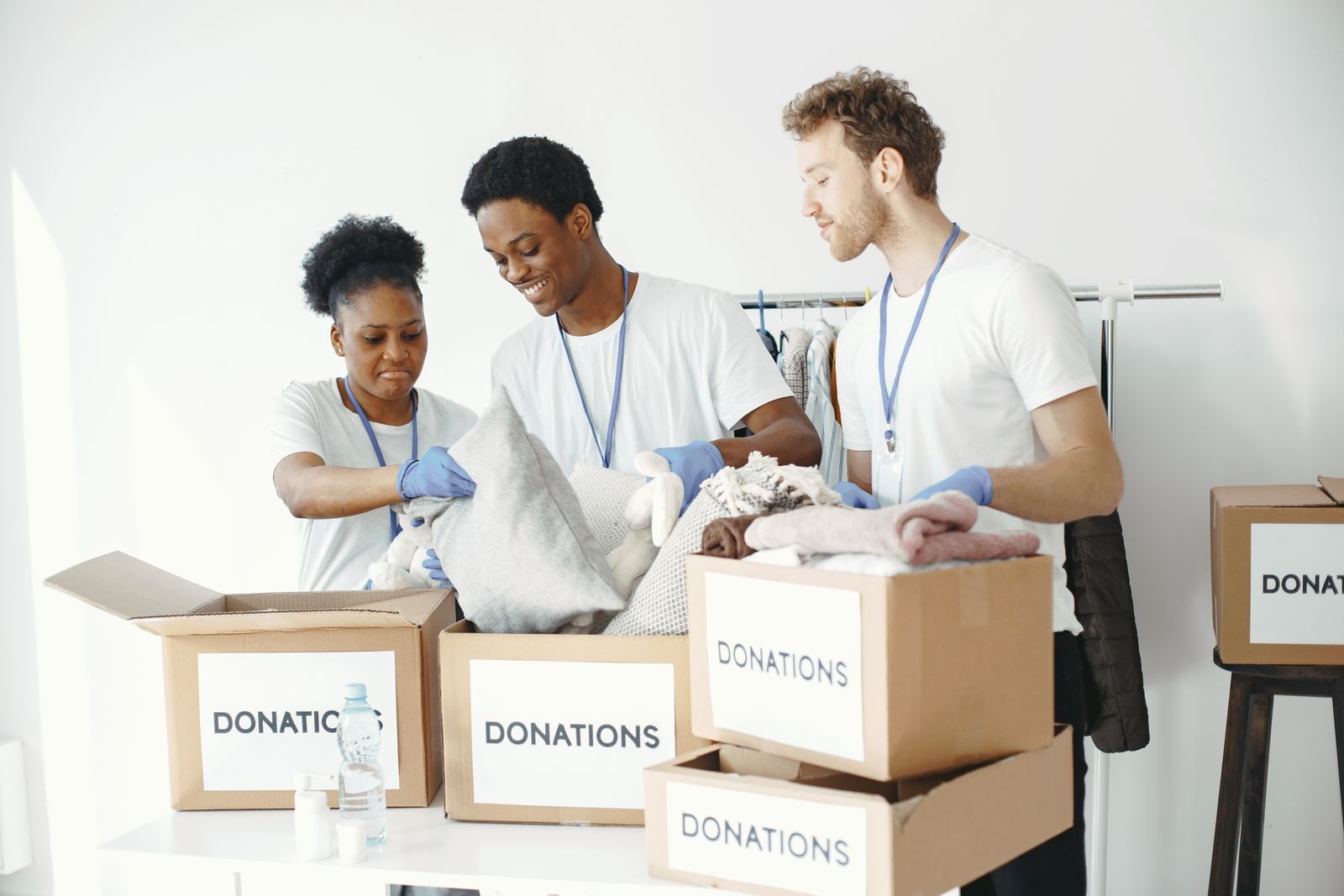 A diverse group of volunteers organizes donation boxes with clothing items indoors